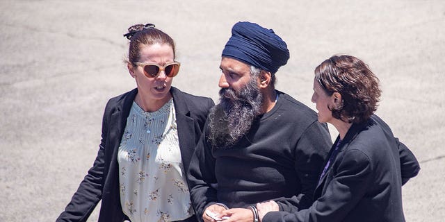 Rajwinder Singh, centro, es escoltado a un automóvil en el aeropuerto de Cairns en Australia el 2 de marzo de 2023. El ciudadano indio Singh será juzgado por asesinato dos años después de que Australia solicitó por primera vez su extradición desde India. 