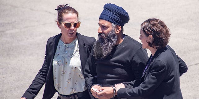 Rajwinder Singh, center, is escorted to a vehicle at Cairns Airport in Australia on March 2, 2023. Indian national Singh will stand trial for a murder two years after Australia first applied for his extradition from India.