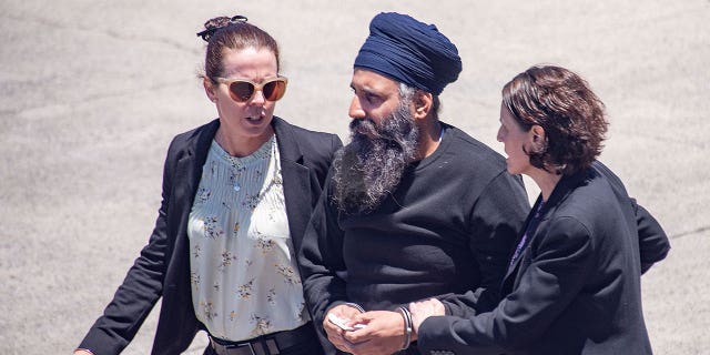 Rajwinder Singh, center, is escorted to a vehicle at Cairns Airport in Australia on March 2, 2023. Indian national Singh will stand trial for a murder two years after Australia first applied for his extradition from India. 