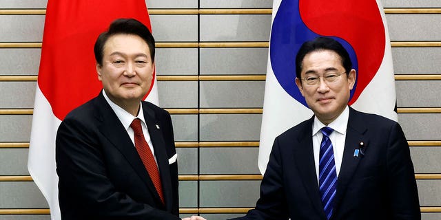 South Korean President Yoon Suk Yeol, left, and Japanese Prime Minister Fumio Kishida, right, shake hands ahead of their bilateral meeting in Tokyo, Japan, on March 16, 2023. 