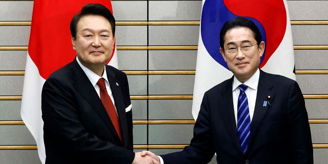 South Korean President Yoon Suk Yeol, left, and Japanese Prime Minister Fumio Kishida, right, shake hands ahead of their bilateral meeting in Tokyo, Japan, on March 16, 2023.