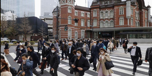 La gente camina por una intersección cerca de la estación de Tokio el 13 de marzo de 2023. Japón canceló su orden el lunes por primera vez en tres años, ya que el país relajó las reglas de COVID-19 en los espacios públicos.