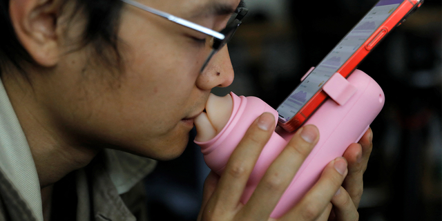 Jing Zhiyuan uses a remote kissing device "Long Lost Touch," as he demonstrates for camera how to use it during an interview with Reuters, at his home in Beijing March 12, 2023.