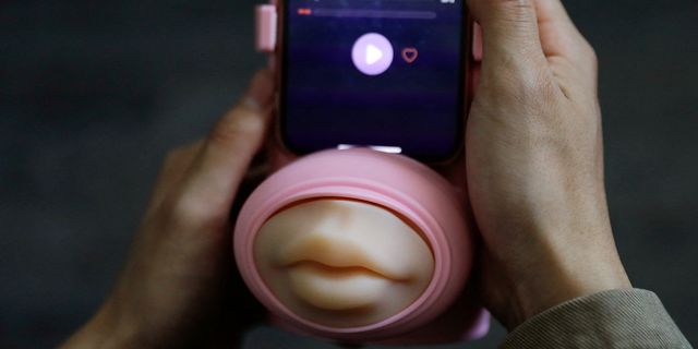 Jing Zhiyuan uses a remote kissing device "Long Lost Touch," as he demonstrates how to use it during an interview with Reuters, at his home in Beijing March 12, 2023.