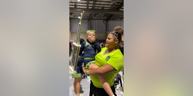 Still surprised by her award-winning solo performance, Peyton Thorsby gets a hug from one of the student coaches from her gym.