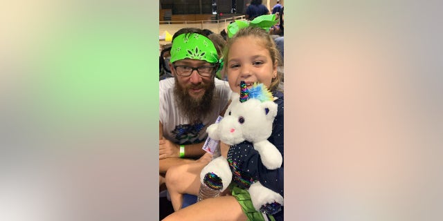 Hugging a stuffed animal, Peyton Thorsby shared a moment with one of cheer coaches, Josh DeMello, after the competition. 