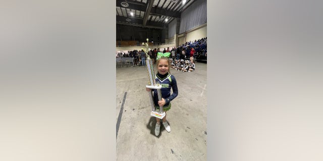 With a big smile on her face, Peyton Thorsby shows off the first-place trophy she earned when she competed solo at a cheer competition.