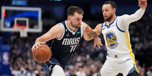 #77 Luka Doncic of the Dallas Mavericks dribbles against #30 Stephen Curry of the Golden State Warriors on March 22, 2023 at the American Airlines Center in Dallas, Texas. 