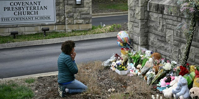 Kneeling woman prays at a makeshift memorial