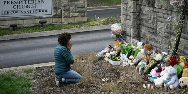 Kneeling woman prays at a makeshift memorial