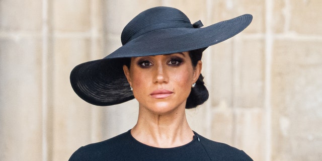 Meghan Markle trägt bei der Beerdigung von Queen Elizabeth ein schwarzes Kleid und einen schwarzen Hut.