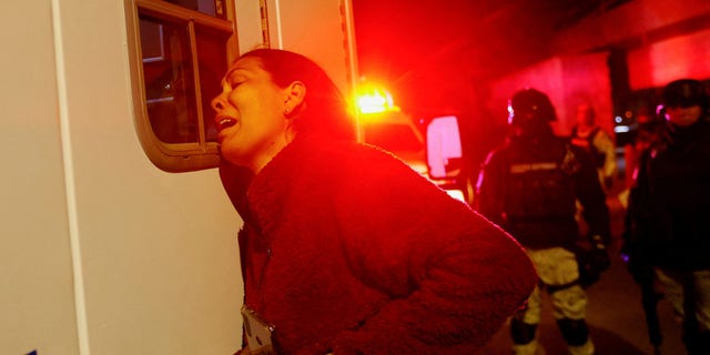 Viangli, a Venezuelan immigrant, reacts outside an ambulance for her injured husband, Eduardo Caraballo, while Mexican authorities and firefighters arrive from inside the National Institute of Migration (INM) building in Ciudad Juárez, Mexico. , carrying out wounded migrants (mainly Venezuelans).