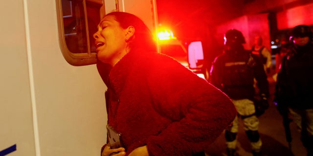 Viangly, a Venezuelan migrant, reacts outside an ambulance for her injured husband Eduard Caraballo while Mexican authorities and firefighters remove injured migrants, mostly Venezuelans, from inside the National Migration Institute (INM) building during a fire, in Ciudad Juarez, Mexico.