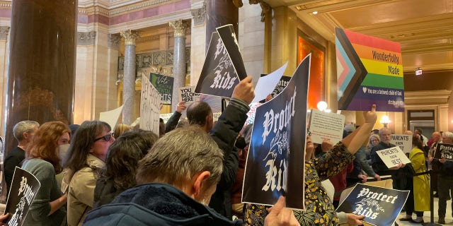 Protesters hold signs as they chant for and against a bill that would make Minnesota a trans refuge state, and strengthen protections for kids and their families who come to the state for gender-affirming care, outside the room where lawmakers would vote on the bill at the state capitol, Thursday, March 23, 2023, in St. Paul, Minnesota.