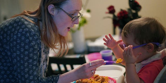 Lauren Hackney feeds her 1-year-old daughter chicken and macaroni during a supervised visit at their apartment in Oakdale, Pennsylvania, on Nov. 17, 2022.