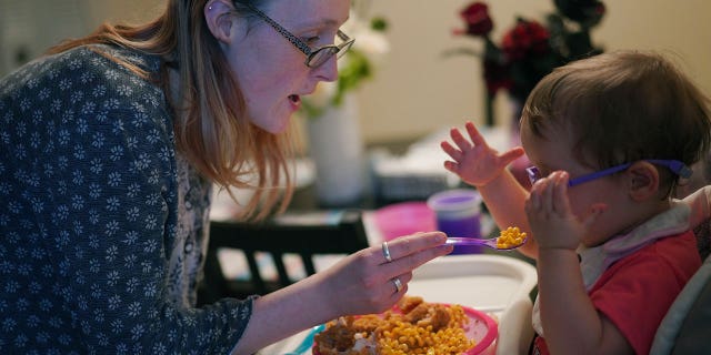 Lauren Hackney feeds her 1-year-old daughter chicken and macaroni during a supervised visit at their apartment in Oakdale, Pennsylvania, on Nov. 17, 2022.