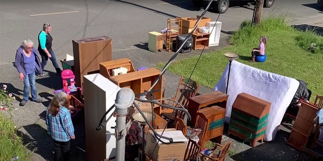 Accused squatters stand in a Northern California driveway near furniture and other belongings