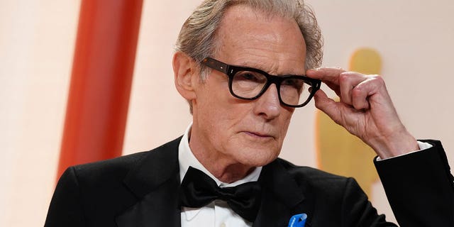 Bill Nighy arrives at the Oscars while wearing a small blue ribbon on March 12, 2023, at the Dolby Theatre in Los Angeles. 