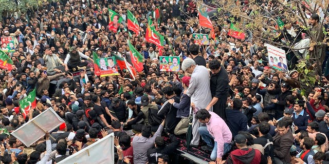 Supporters gather around a car carrying former Pakistani Prime Minister Imran Khan (not pictured) after he appeared in court on February 28, 2023. 