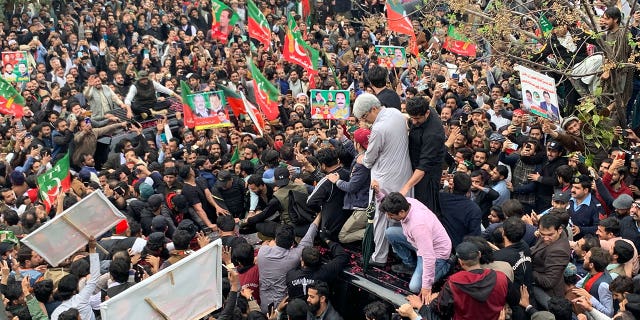 Supporters gather around a car carrying former Pakistani Prime Minister Imran Khan (not pictured) after he appeared in court on February 28, 2023. 