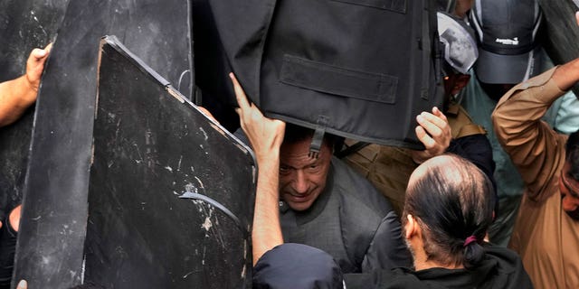 El personal de seguridad lleva chalecos antibalas para proteger al ex primer ministro Imran Khan, centro, después de que compareciera ante un tribunal en Lahore, Pakistán, el 21 de marzo de 2023.