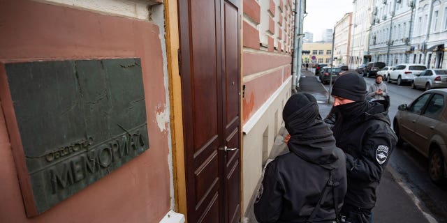 Two Russian police officers stand in front of the door of the Memorial office in Moscow, Russia, on March 21, 2023. Russian authorities raided homes and offices of human rights advocates and historians associated with the prominent rights group Memorial that won the Nobel Peace Prize last year.