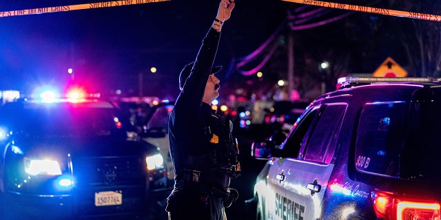 sacramento county sheriffs deputy holds crime scene tape over car