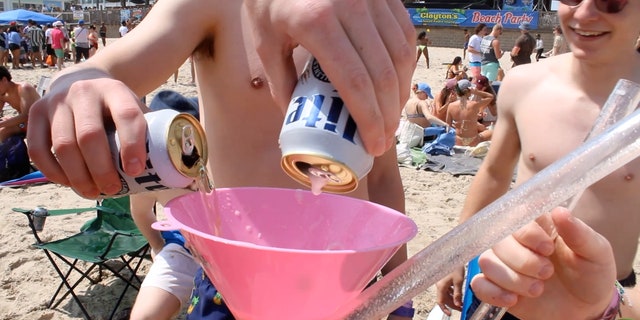 A group of college boys get ready to show off their beer funneling skills on the beaches of South Padre Island. 