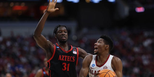 Brandon Miller (24) of the Alabama Crimson Tide controls the ball against Nathan Mensah (31) of the San Diego State Aztecs during the first half in the Sweet 16 of the NCAA Tournament at KFC YUM! Center March 24, 2023, in Louisville, Ky.