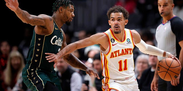 El escolta de los Boston Celtics, Marcus Smart, a la izquierda, defiende al escolta de los Atlanta Hawks, Trae Young, durante la segunda mitad de un partido de baloncesto de la NBA, el sábado 11 de marzo de 2023, en Atlanta. 