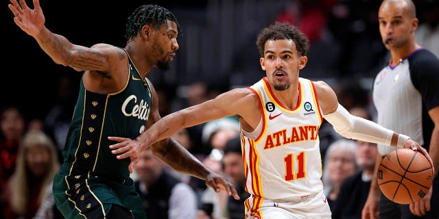 El escolta de los Boston Celtics, Marcus Smart, a la izquierda, defiende al escolta de los Atlanta Hawks, Trae Young, durante la segunda mitad de un partido de baloncesto de la NBA, el sábado 11 de marzo de 2023, en Atlanta. 