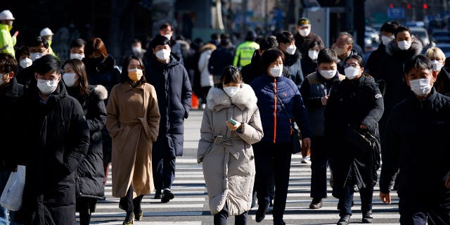 Commuters cross a street in Seoul, South Korea, on Feb. 3, 2021.