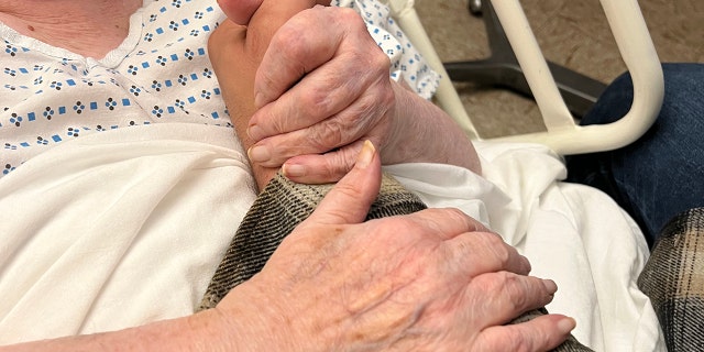 A closeup of Alice Schuman holding hands with Brock Cvijanovich, the new owner of her building who looked after her — she had no one else in her life.