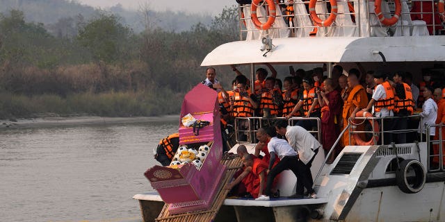 Family members, accompanied by monks and fellow mourners, release the ashes of Duangphet Phromthep in a makeshift boat along with soccer balls and some of his prized possessions into the Mekong River in Thailand on March 6, 2023. 