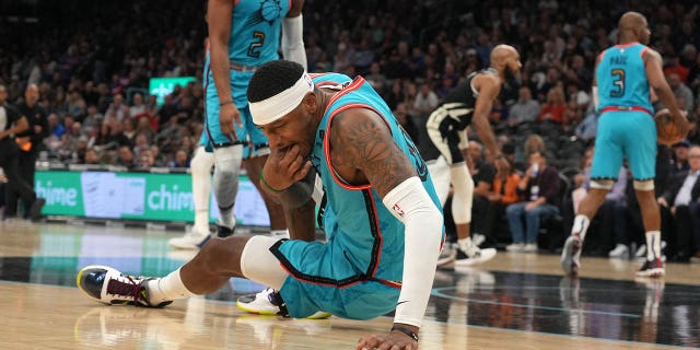 Phoenix Suns forward Torrey Craig (0) retrieves a tooth from the court during a game against the Milwaukee Bucks at Footprint Center.