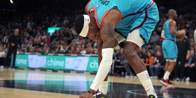 Phoenix Suns forward Torrey Craig (0) retrieves his tooth from the court during a game against the Milwaukee Bucks at Footprint Center. 