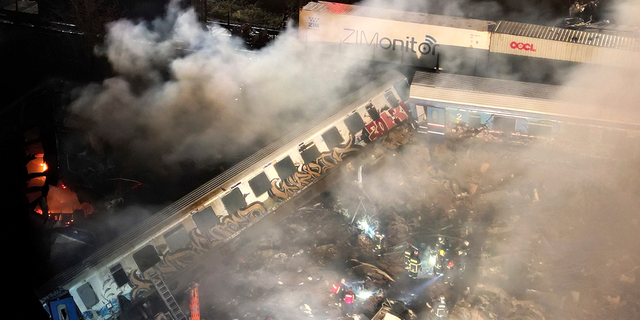 Smoke rises from trains as firefighters and rescuers operate after a collision near Larissa city, Greece.