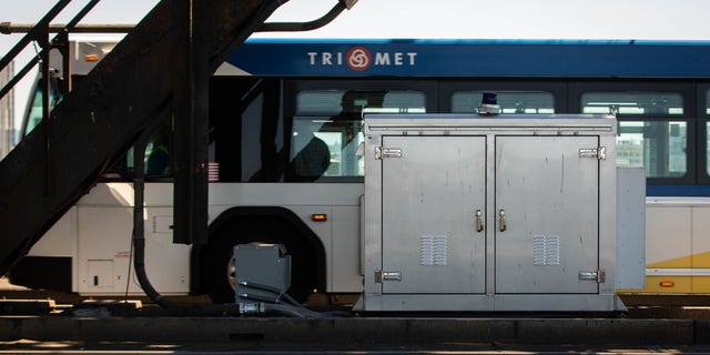 A TriMet bus drives past a MAX rail electrical box in Portland, Oregon.