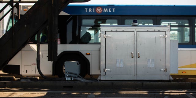 A TriMet bus drives past a MAX rail electrical box in Portland, Oregon.