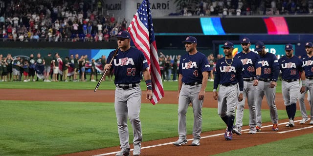 Mike Trout leads his teammates as he carries the American flag before the game against Japan at LoanDepot Park on March 21, 2023 in Miami.