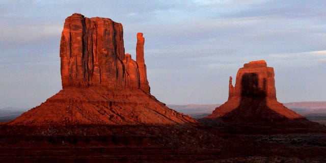 A sunset spectacle featuring two mitten-shaped rock formations crosses Monument Valley Tribal Park from the Visitors Center in Oljato-Monument Valley, Arizona, on March 29, 2023.
