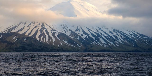 The Tanaga Volcano sits beneath clouds near Adak, Alaska, on May 23, 2021. A swarm of earthquakes occurring over the past few weeks has intensified at a remote Alaska volcano dormant for over a century.