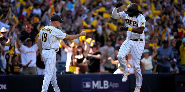 Josh Bell #24 of the San Diego Padres celebrate with third base coach Matt Williams #18 as he rounds the bases after hitting a home run in the second inning of Game 2 of the NLCS between the Philadelphia Phillies and the San Diego Padres at Petco Park on October 19, 2022 in San Diego, California.