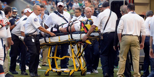El ala defensiva de los Denver Broncos Derek Wolfe (95) es examinado por el personal médico después de sufrir una lesión en el primer trimestre contra los Seattle Seahawks el 17 de agosto de 2013 en el CenturyLink Field.  Wolfe fue puesto en una ambulancia y llevado al hospital. 