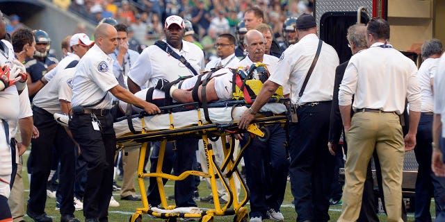 El ala defensiva de los Denver Broncos Derek Wolfe (95) es examinado por el personal médico después de sufrir una lesión en el primer trimestre contra los Seattle Seahawks el 17 de agosto de 2013 en el CenturyLink Field.  Wolfe fue puesto en una ambulancia y llevado al hospital. 