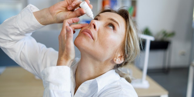 Woman putting in eye drops