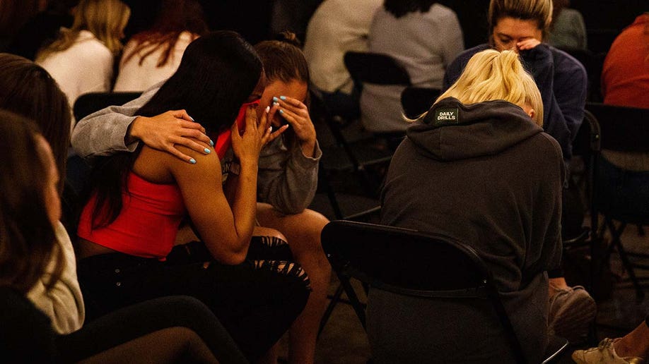 Two women cry together during a vigil at Church of the City