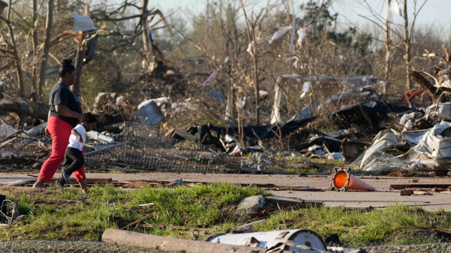 A pair of residents walk through the remains of their mobile home
