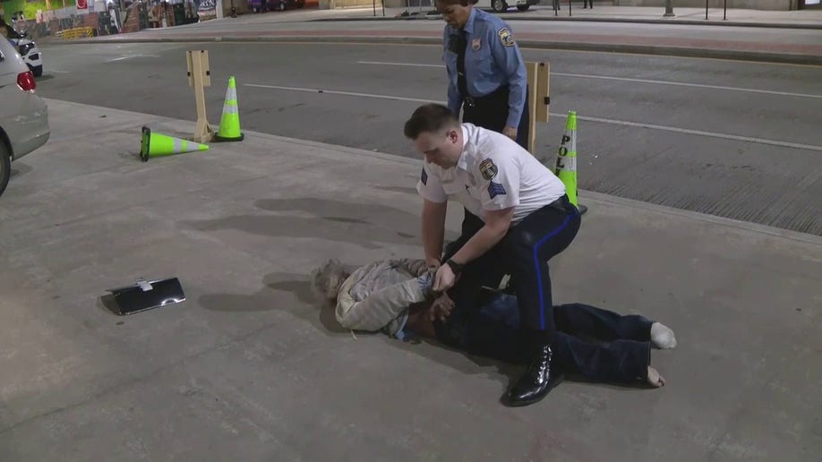 officer handcuffing man on sidewalk