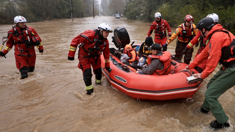 Sonoma County Fire District firefighters and a sheriff's deputy pull people in a boat in Guerneville